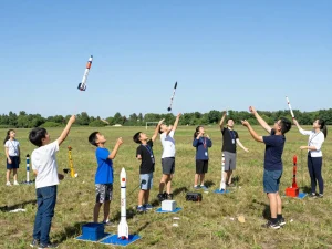 Participants launching model rockets in a sunny outdoor field showcasing the joy of model rockets education and community engagement.